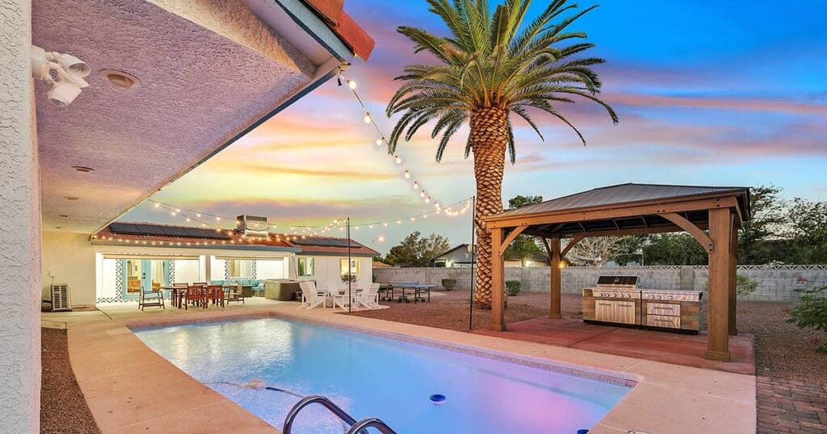 Private pool, outdoor kitchen, and gazebo at a vegasbnb Las Vegas vacation home at sunset